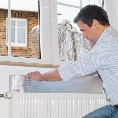 Posa del pannello termoriflettente dietro il termosifone sotto la finestra