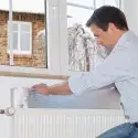 Anbringen des Reflexionspaneels hinter dem Heizkörper unter dem Fenster
